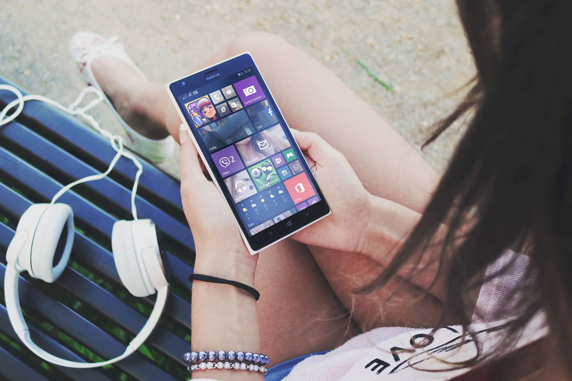 Apps de bem-estar emocional gratuitos — Close-up de uma mulher usando um smartphone Windows com fones de ouvido ao ar li
