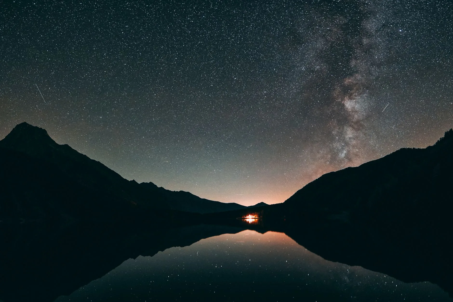 Atividades para elevar o astral — Um deslumbrante céu estrelado com a Via Láctea sobre um lago montanhoso calmo, mostran